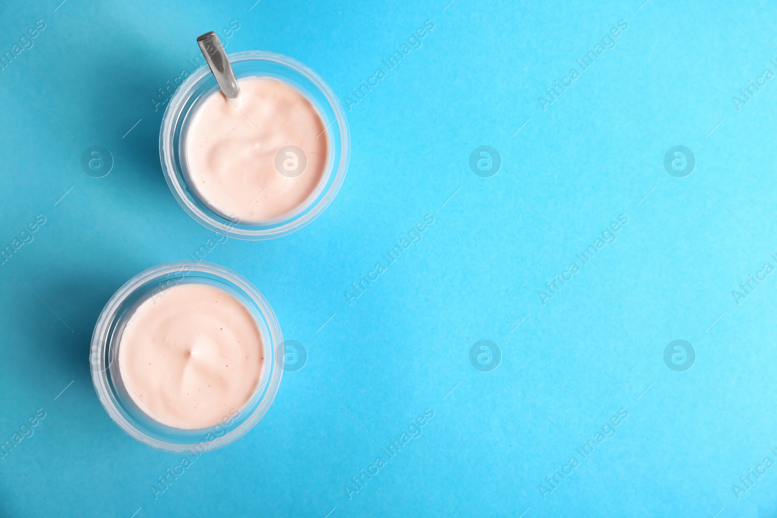 Photo of Plastic cups with tasty yogurt on color background, top view