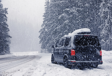 Photo of Modern car on snowy road near forest. Winter vacation