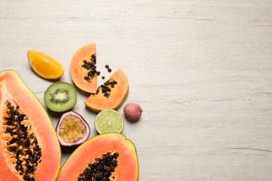 Photo of Fresh ripe papaya and other fruits on wooden table, flat lay. Space for text