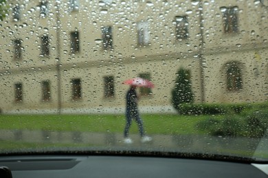 Photo of Blurred view of city street through wet car window. Rainy weather