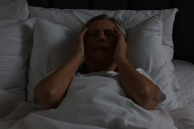 Photo of Woman suffering from headache in bed at night