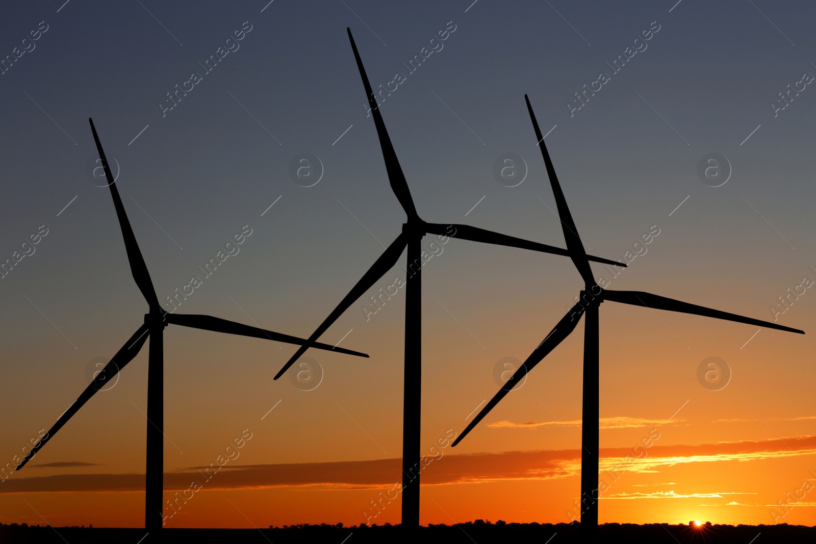 Image of Silhouettes of wind turbines at sunset. Alternative energy source