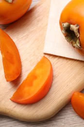 Photo of Delicious ripe persimmons on light wooden table, top view