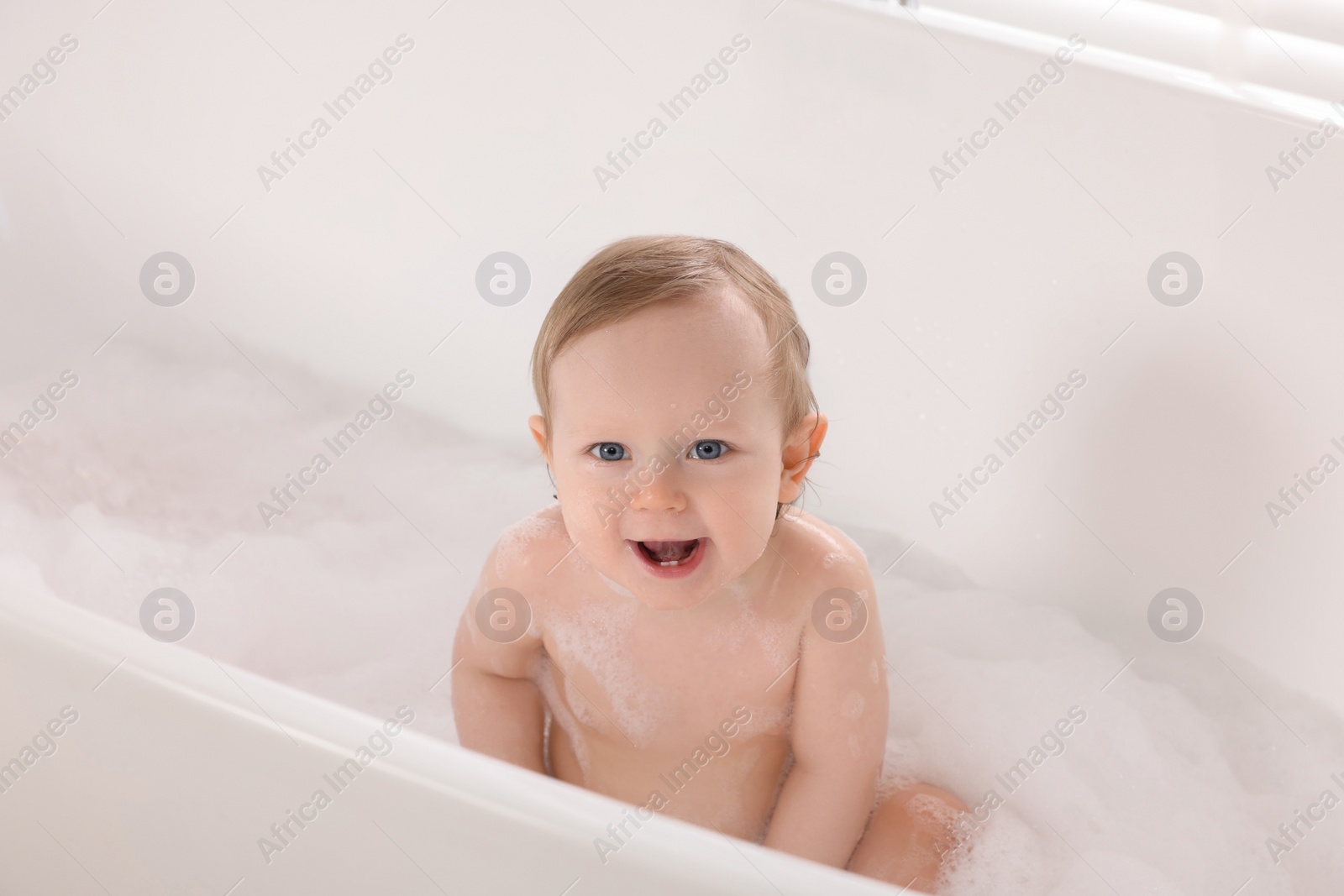 Photo of Cute little baby bathing in tub at home
