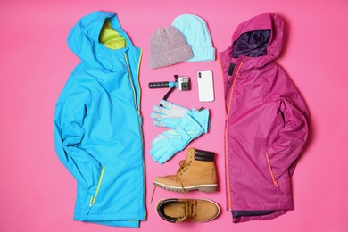 Photo of Flat lay composition with warm clothes for winter vacation on color background