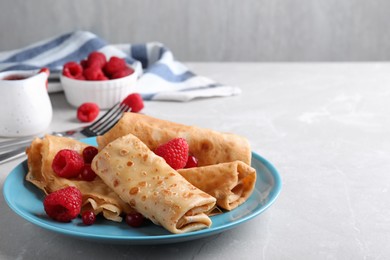 Photo of Delicious crepes served with berries on light grey table. Space for text