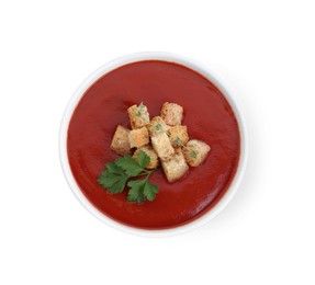 Photo of Delicious tomato cream soup with croutons and parsley in bowl isolated on white, top view