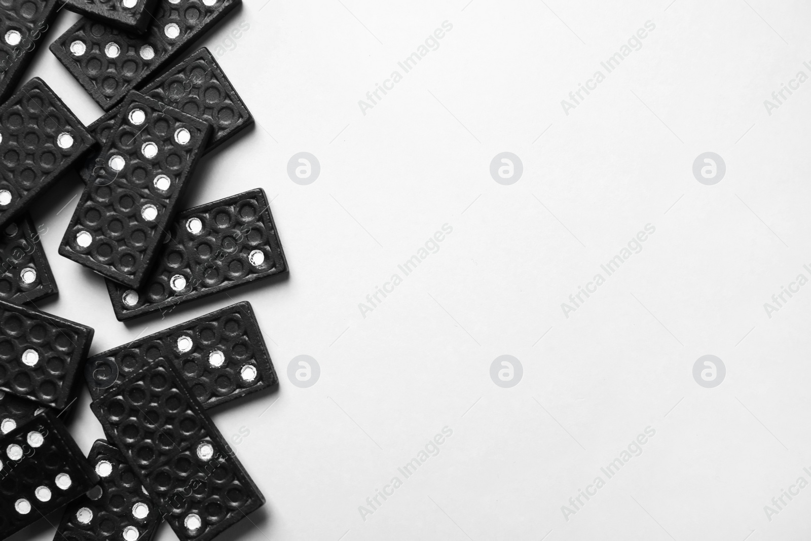 Photo of Black domino tiles on white background, flat lay. Space for text