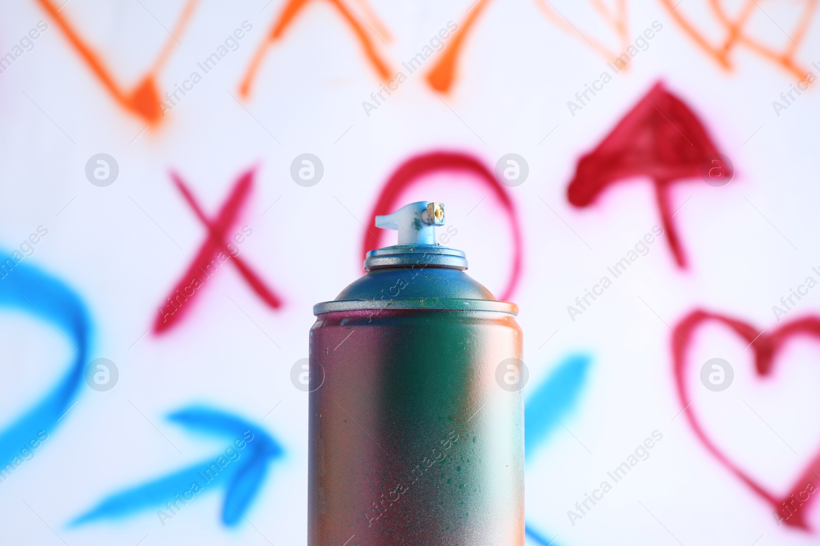 Photo of One spray paint can against white wall with different drawn symbols, closeup