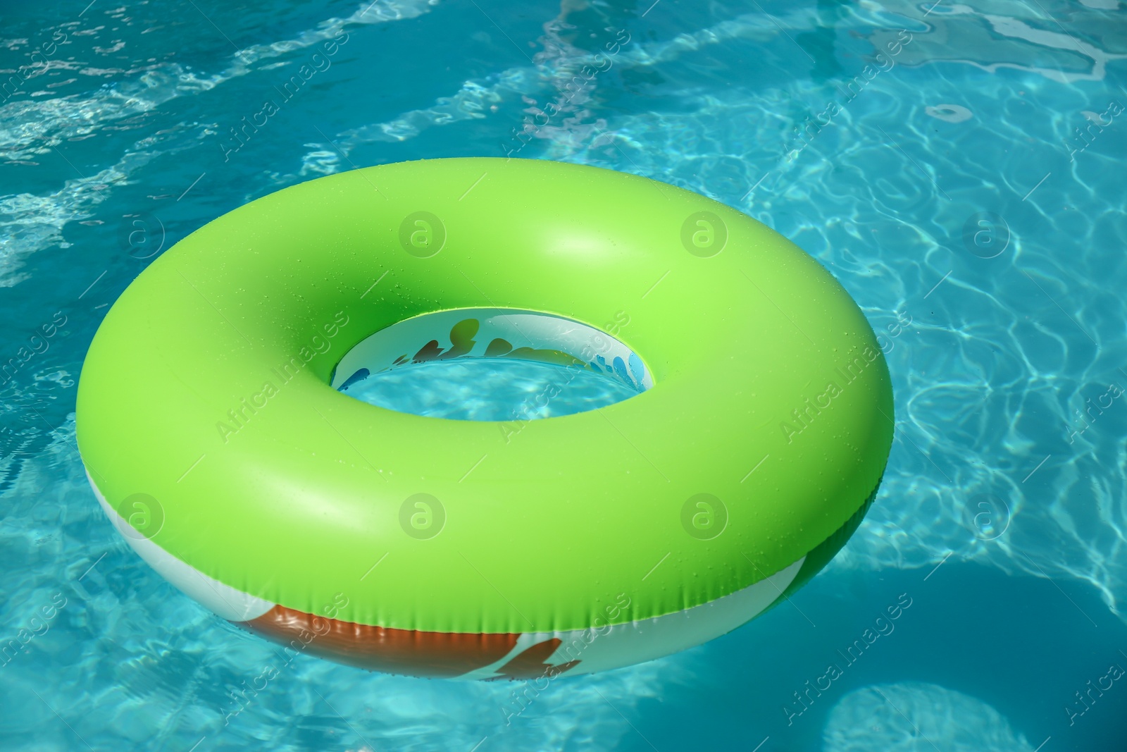 Photo of Bright inflatable ring floating in swimming pool on sunny day