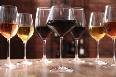 Different tasty wines in glasses on wooden table