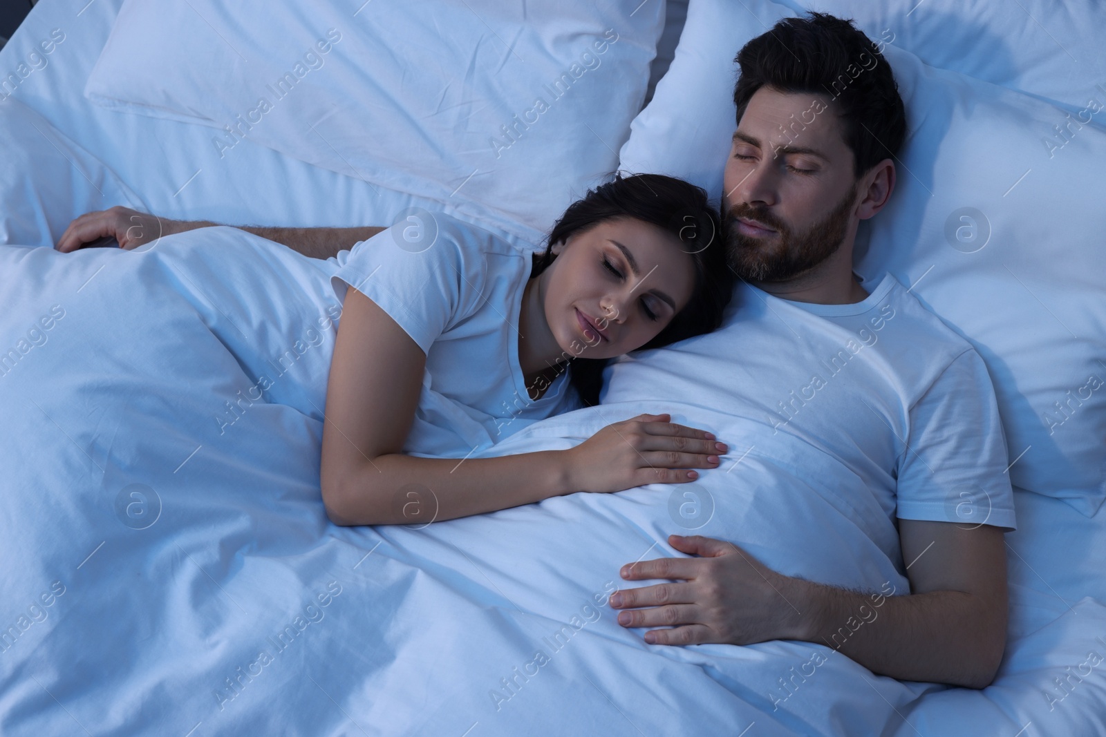 Photo of Lovely couple sleeping together in bed at night, top view