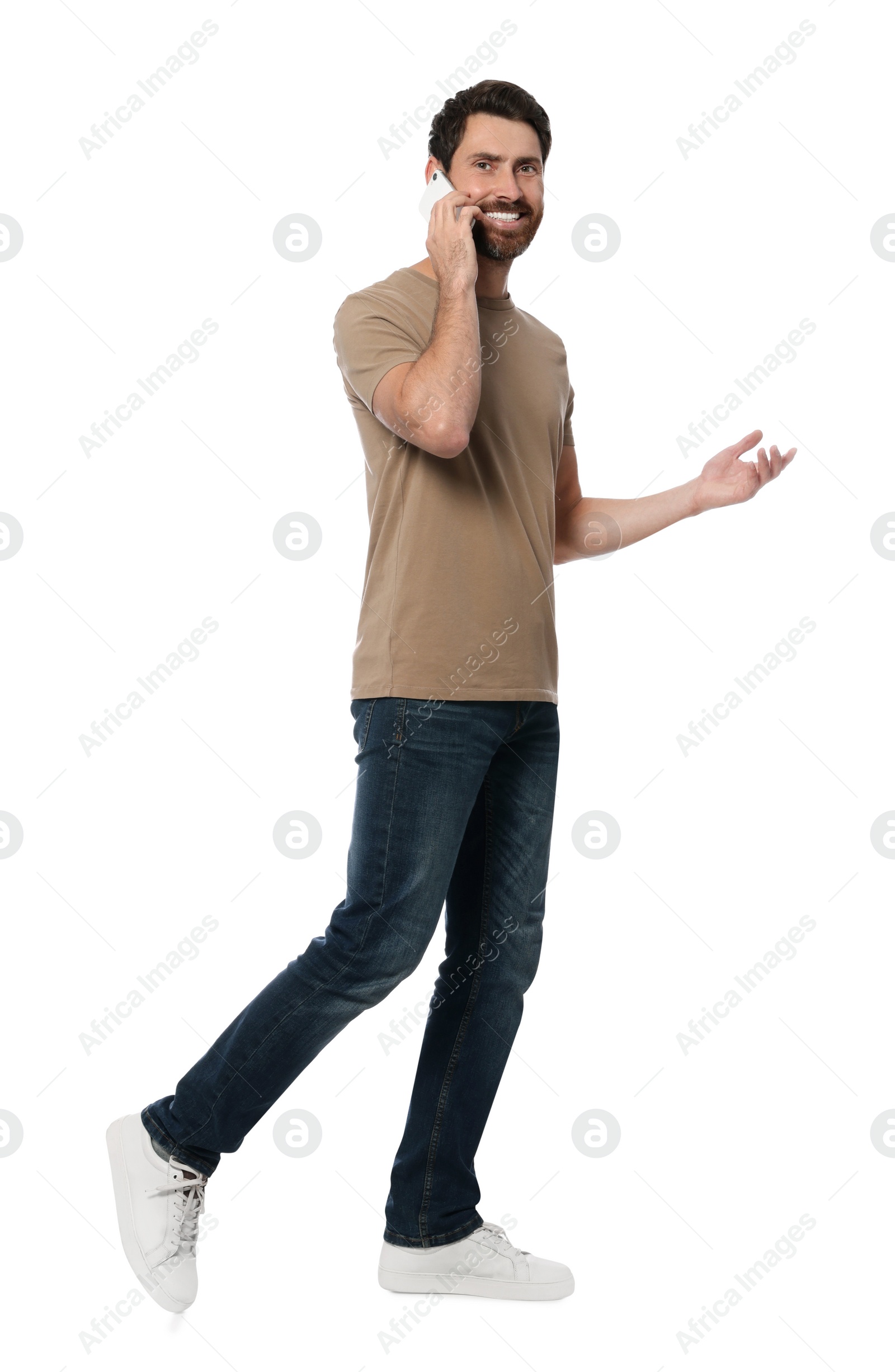 Photo of Handsome man talking on smartphone while walking against white background