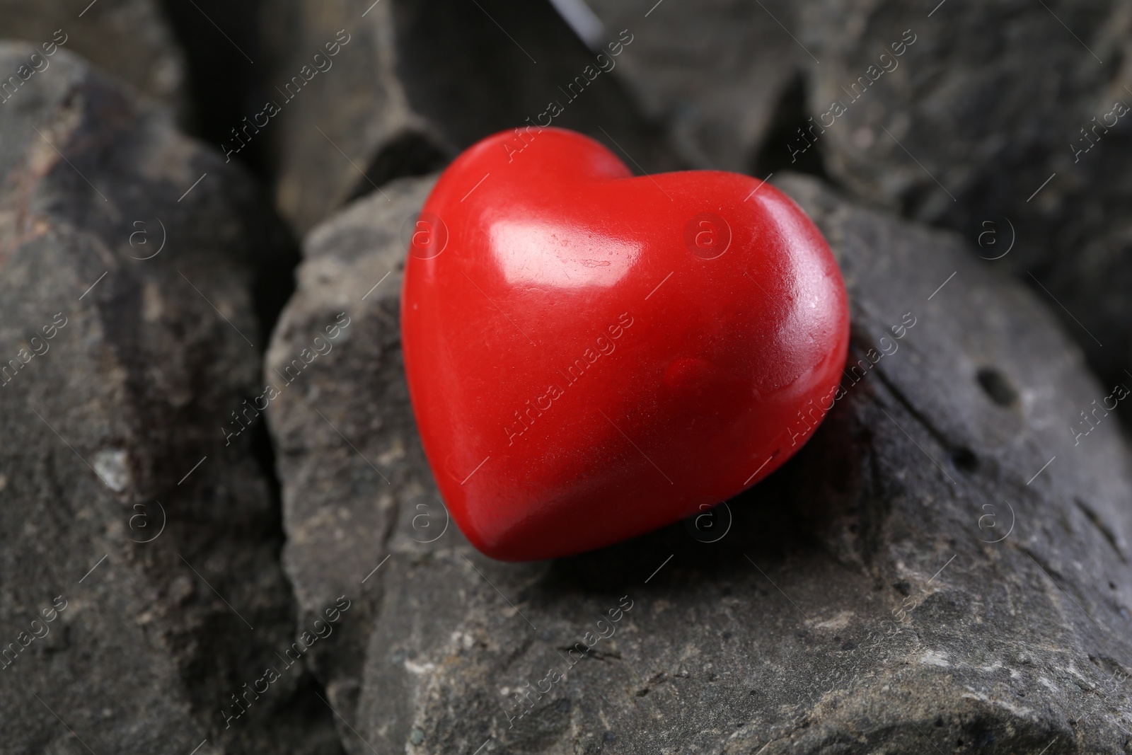 Photo of One red decorative heart on stones, closeup