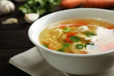 Photo of Plate with fresh homemade chicken soup on table, closeup