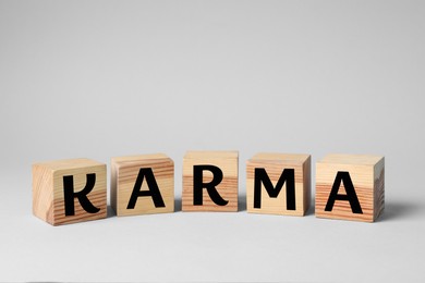 Photo of Word Karma made of cubes with letters on light background