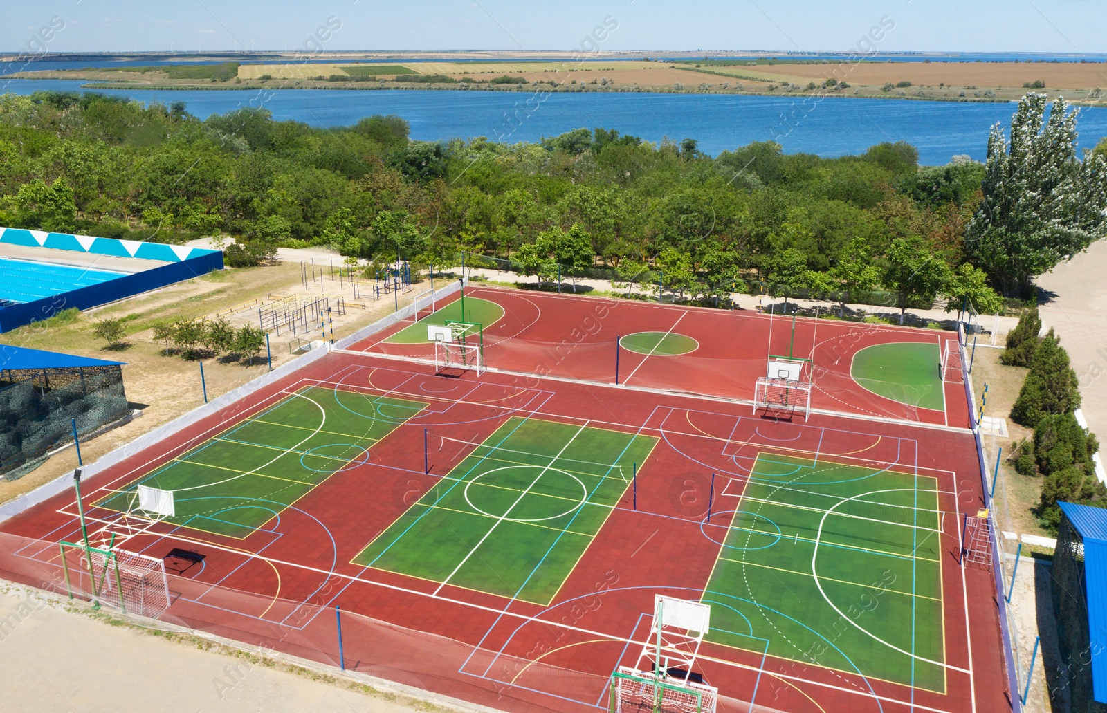 Image of Outdoor sports complex near bay on sunny day, aerial view