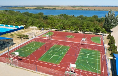 Outdoor sports complex near bay on sunny day, aerial view