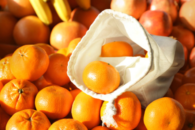 Photo of Cotton eco bag with fruits on tangerines, closeup. Life without plastic