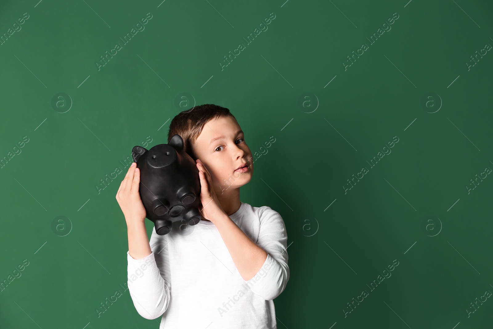 Photo of Little boy with piggy bank on color background. Space for text