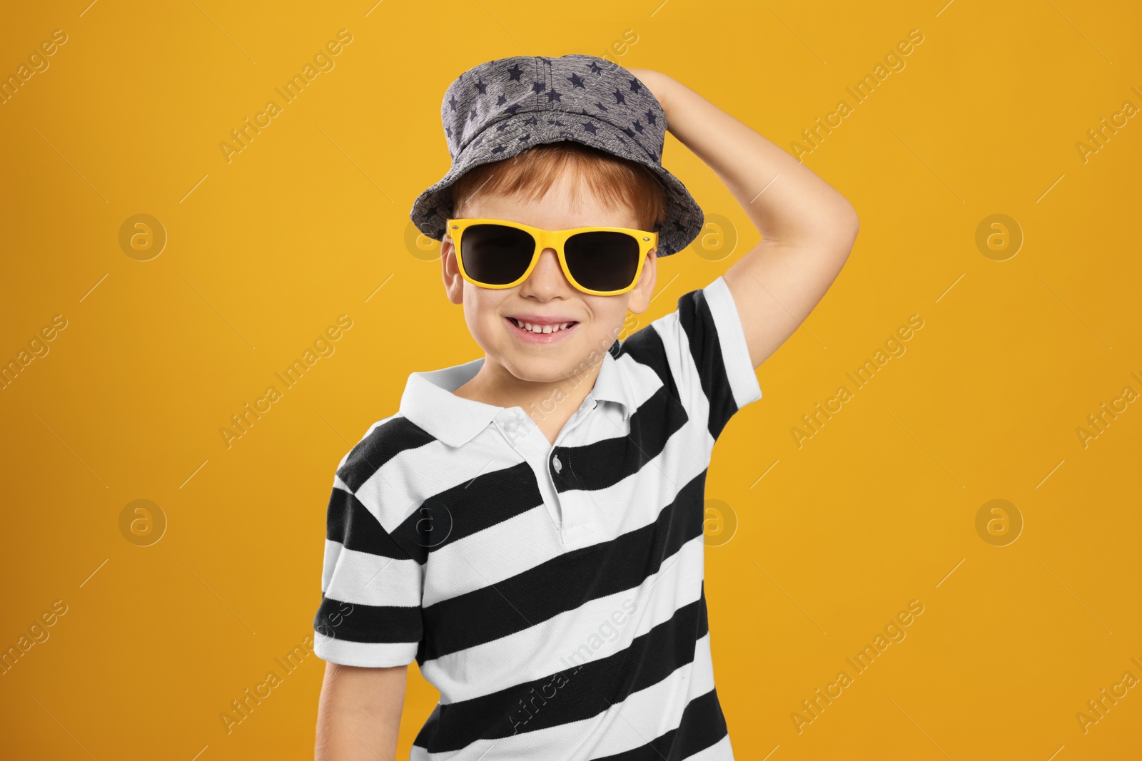 Photo of Cute little boy with sunglasses on yellow background