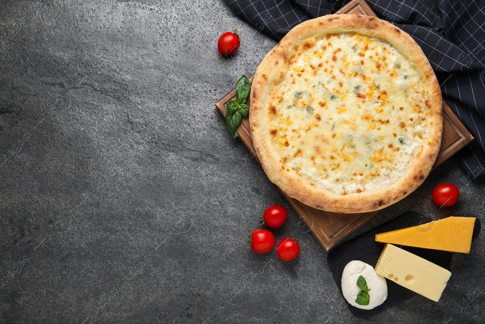 Photo of Delicious cheese pizza and ingredients on dark grey table, flat lay. Space for text