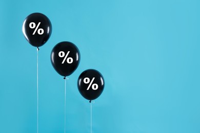 Image of Discount offer. Black balloons with percent sign on light blue background, space for text