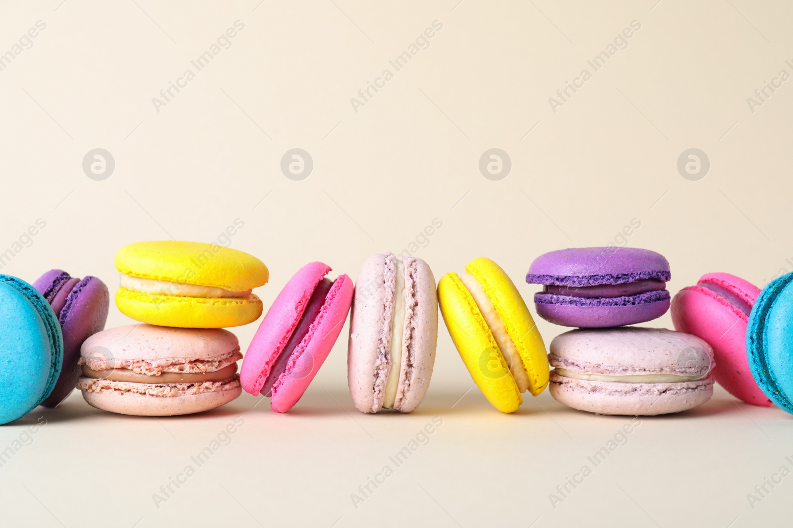 Photo of Delicious fresh colorful macarons on beige background