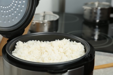 Photo of Modern cooker with fresh boiled rice in kitchen