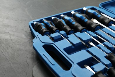 Photo of Set of screwdrivers in open toolbox on dark textured table, closeup