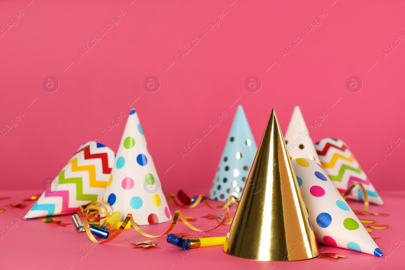 Photo of Many colorful party hats and festive items on pink background