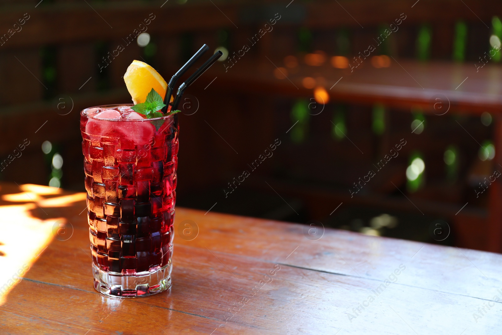 Photo of Glass of delicious cocktail with ice on table in bar