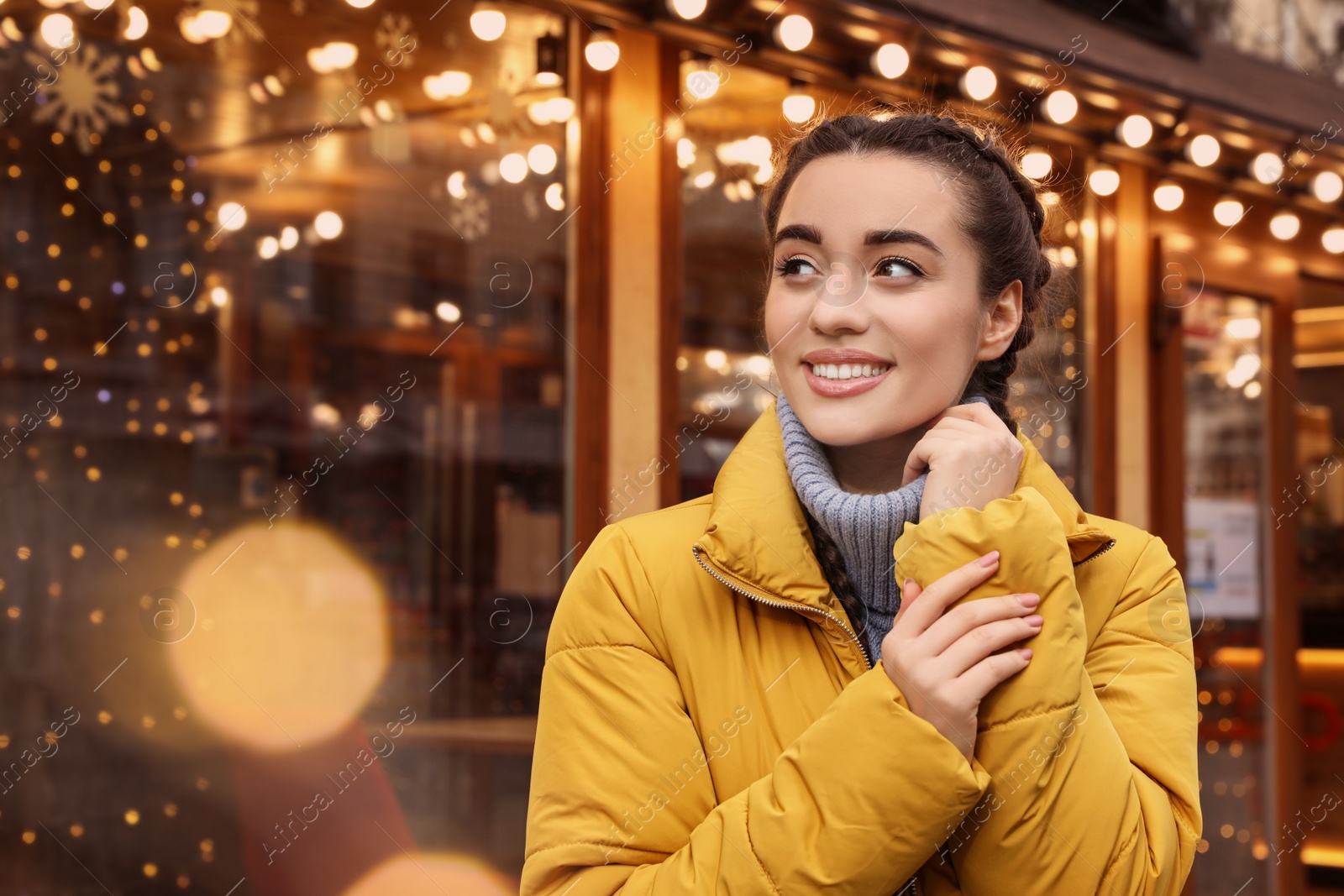 Photo of Young woman near cafe decorated for Christmas