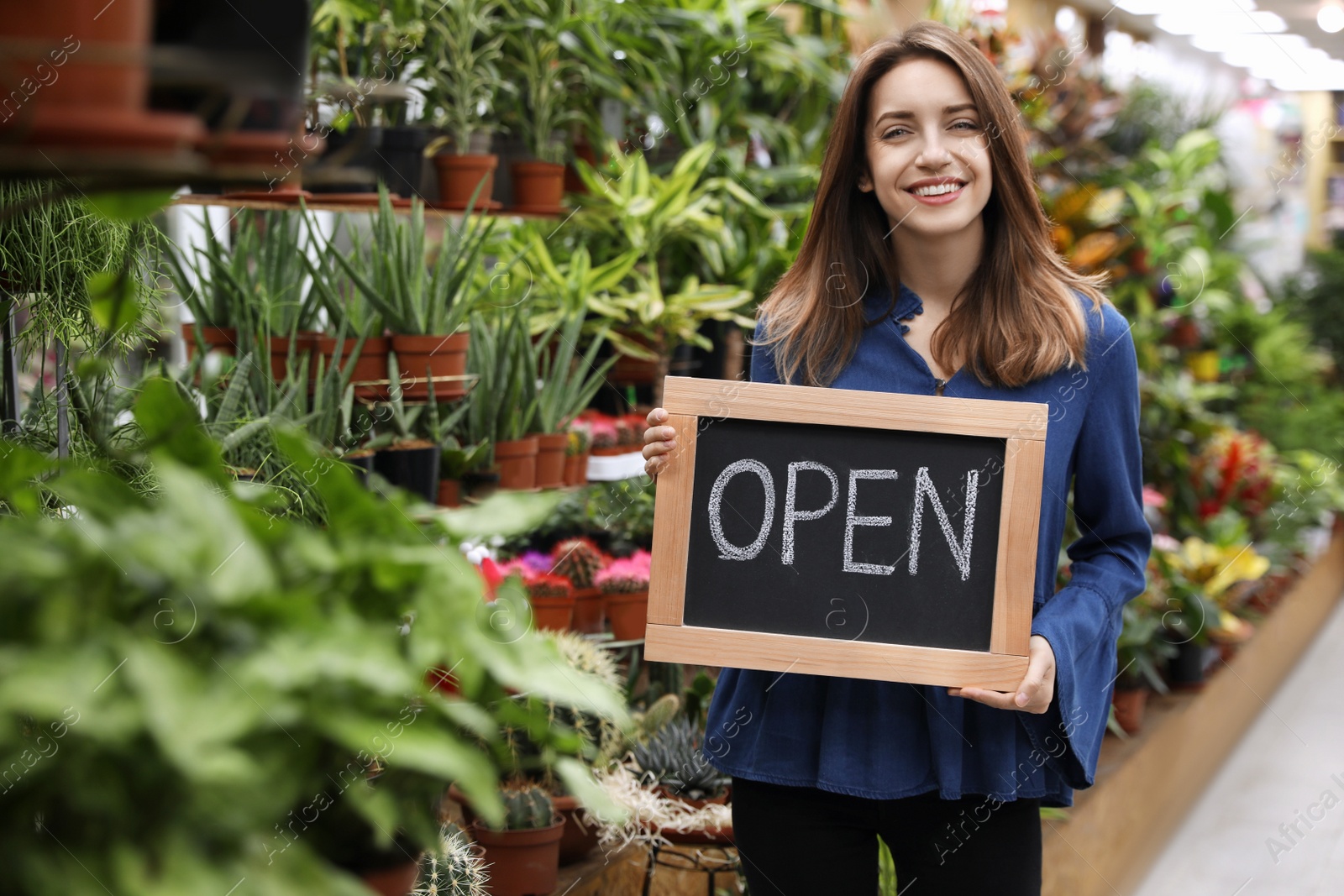 Photo of Young business owner holding OPEN sign in flower shop