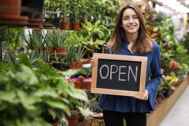 Photo of Young business owner holding OPEN sign in flower shop