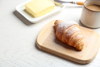 Photo of Board with tasty croissant and powdered sugar on white wooden table. French pastry