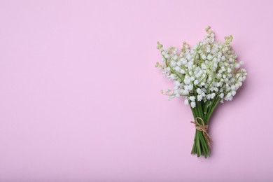 Photo of Beautiful lily of the valley flowers on pink background, top view. Space for text