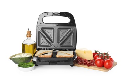 Modern sandwich maker with bread slices and different products on white background