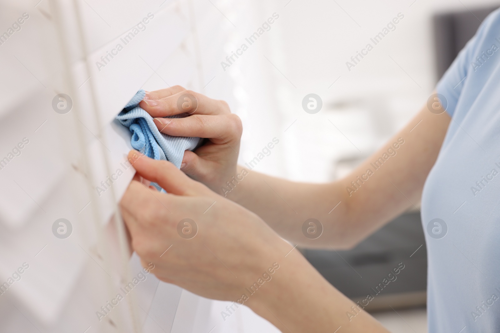 Photo of Woman with microfiber cloth wiping blinds at home, closeup