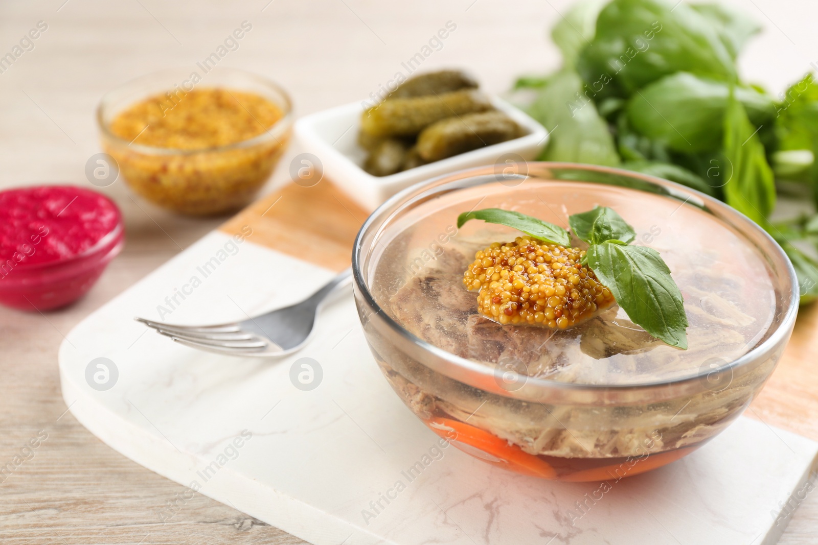 Photo of Delicious aspic with meat and vegetables served on light wooden table, closeup