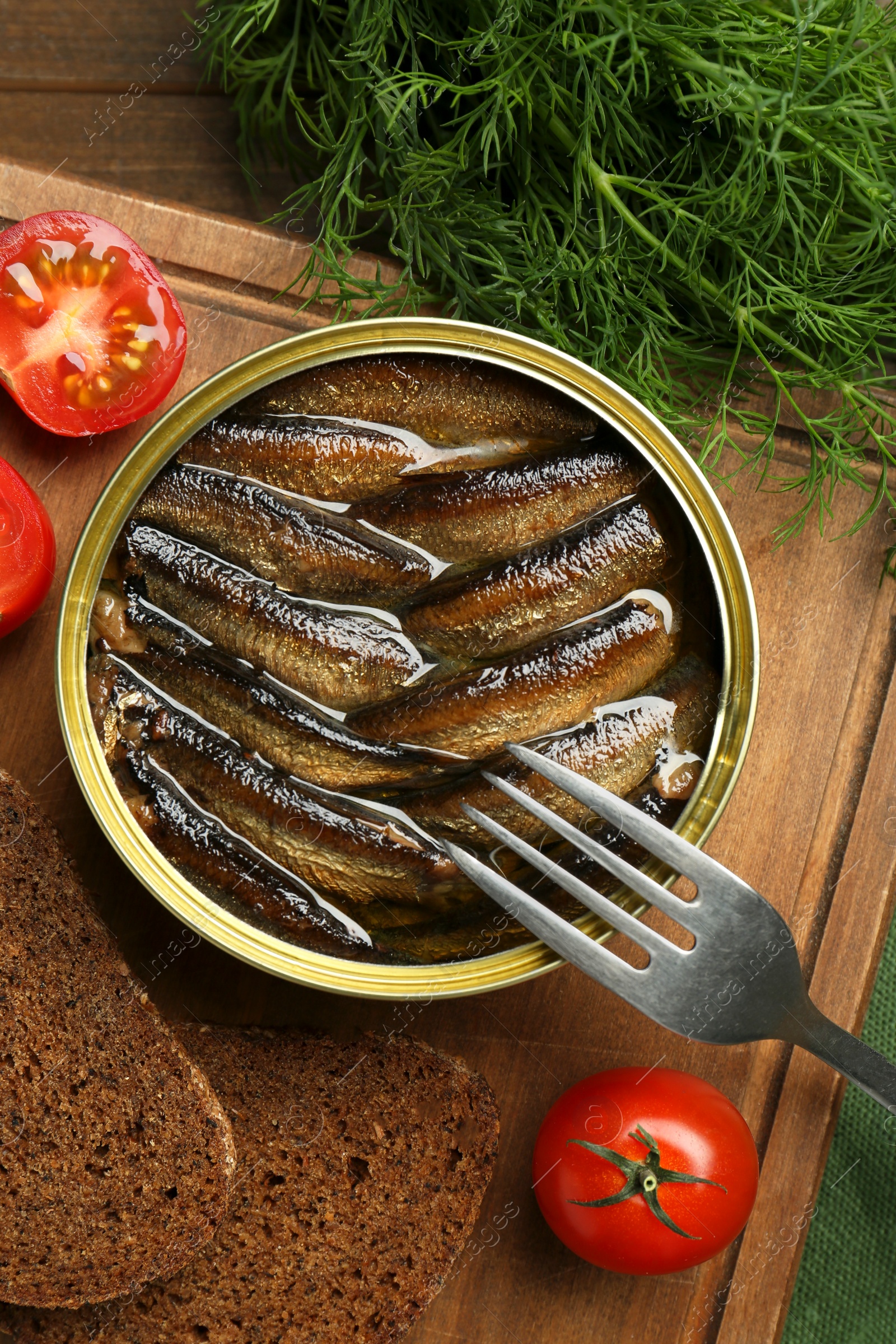 Photo of Tin can with tasty sprats and fork served on table, flat lay