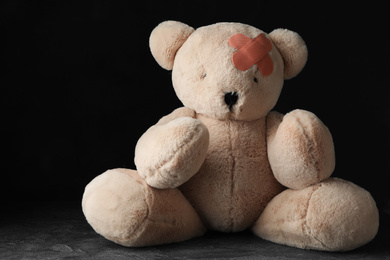 Toy Teddy bear with sticking plasters on grey stone table