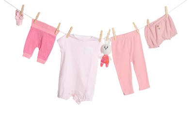 Photo of Different baby clothes and toy bunny drying on laundry line against white background