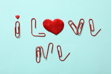 Phrase I Love Me made of clips and red hearts on turquoise background, flat lay