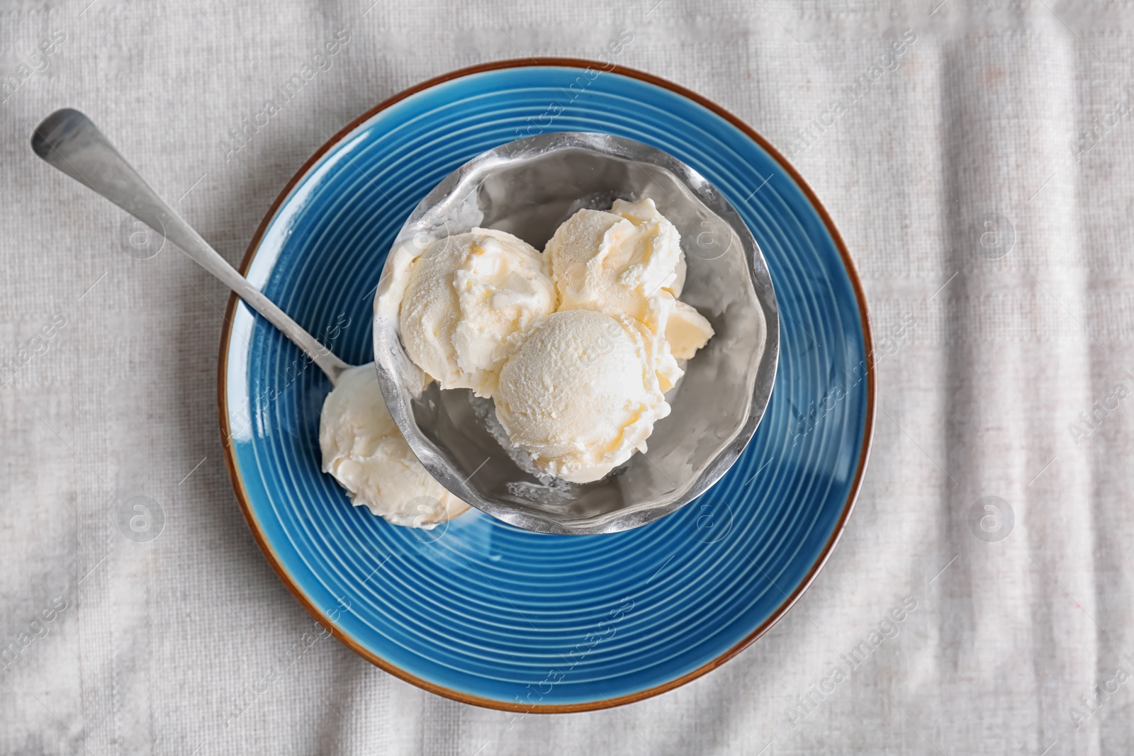 Photo of Bowl and spoon with tasty vanilla ice cream on fabric