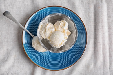 Bowl and spoon with tasty vanilla ice cream on fabric