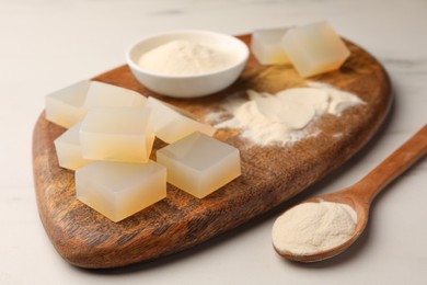 Agar-agar jelly cubes and powder on white marble table, closeup