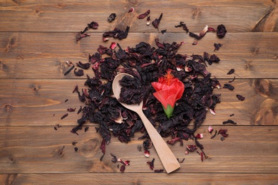 Photo of Dry hibiscus tea, spoon and flower on wooden table, flat lay