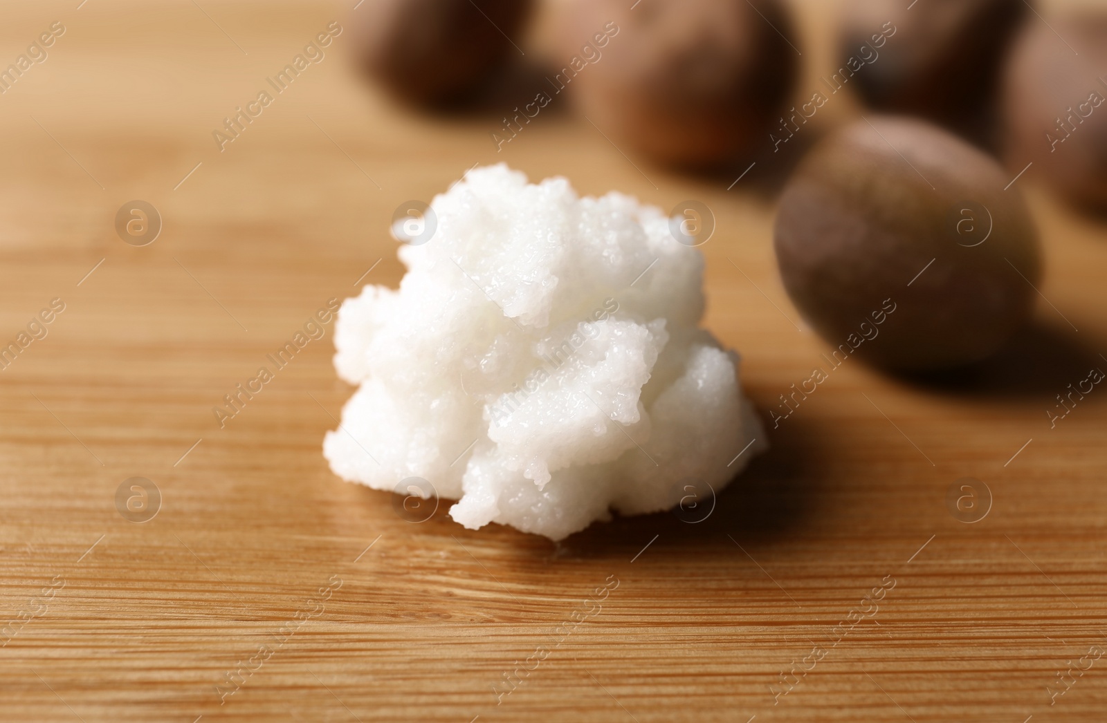 Photo of Fresh shea butter on wooden table, closeup. Cosmetic product