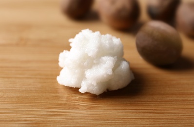 Photo of Fresh shea butter on wooden table, closeup. Cosmetic product